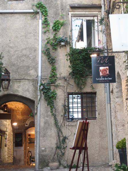 Ivy-covered stone facade with La Galerie des Ours sign and an easel