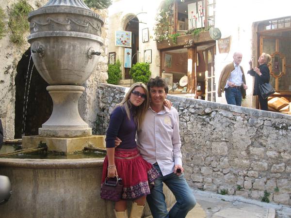 Couple posing beside a stone fountain in a village with art shops