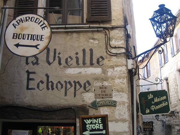 Painted shop signs and wrought-iron lantern in Saint-Paul-de-Vence, Rue de l'Étoile
