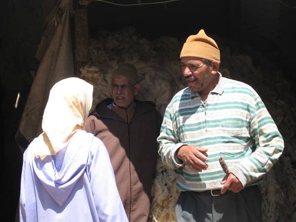 Man in yellow cap and striped shirt talking in front of wool shop