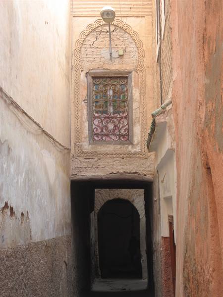 Narrow alley between ochre walls with ornate window and dark archway