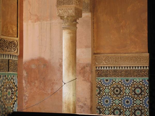 Marble column between ochre walls and floral zellige tiles, likely Marrakech