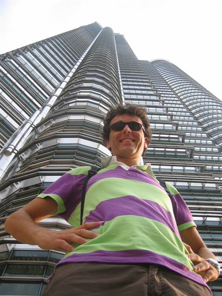 Smiling tourist beneath the Petronas Towers in Kuala Lumpur, steel and glass facades