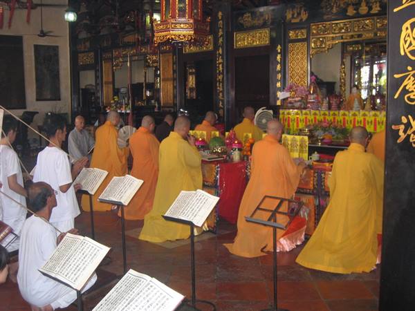 Orange-robed monks chant sutras before the temple altar