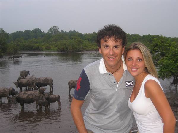 Smiling couple in front of water buffaloes bathing in the river