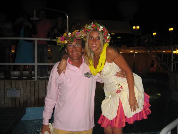 Couple wearing flower crowns and yellow lei by the pool at night