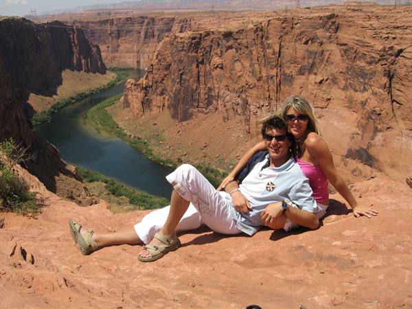 Couple in sunglasses on red rock, Colorado River in canyon, Glen Canyon