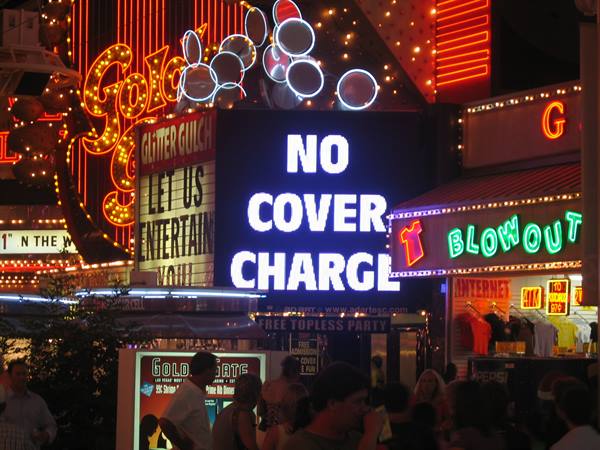 Neon bar signs glowing at night, No Cover Charge sign above a crowd
