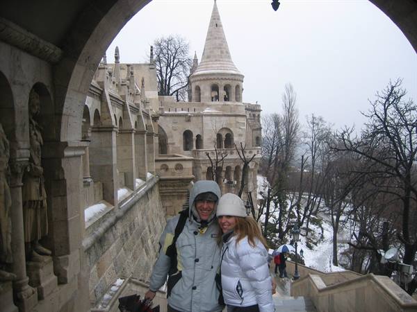 Smiling couple under Fisherman's Bastion arch, snowy trees and neo-Gothic tower