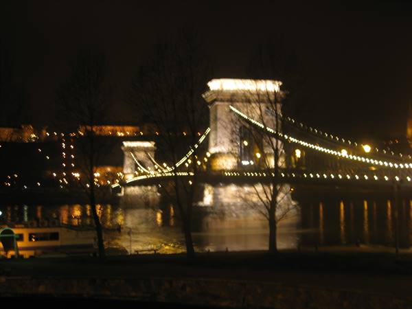 Chain Bridge lit up at night over the Danube, yellow lights reflecting on water