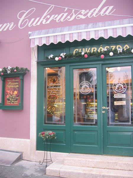 Green storefront of the Cukrászda pastry shop, pink facade, Christmas decorations