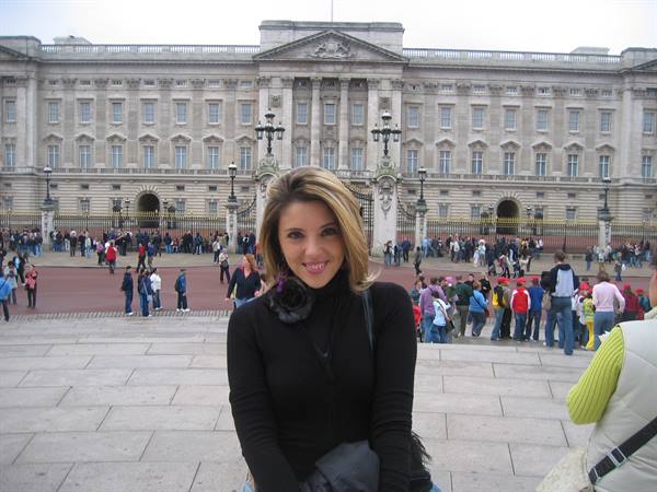 Smiling woman in front of Buckingham Palace, tourists crowding the square