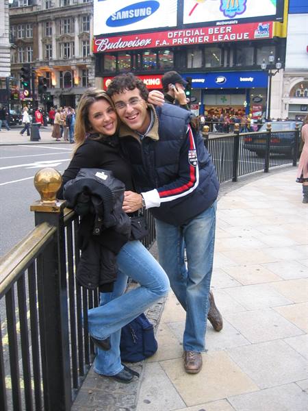 Couple embracing by the railings at Piccadilly Circus, advertising billboards behind