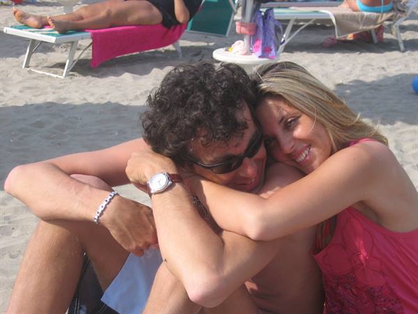 Couple hugging on the sand, sun loungers and towels behind
