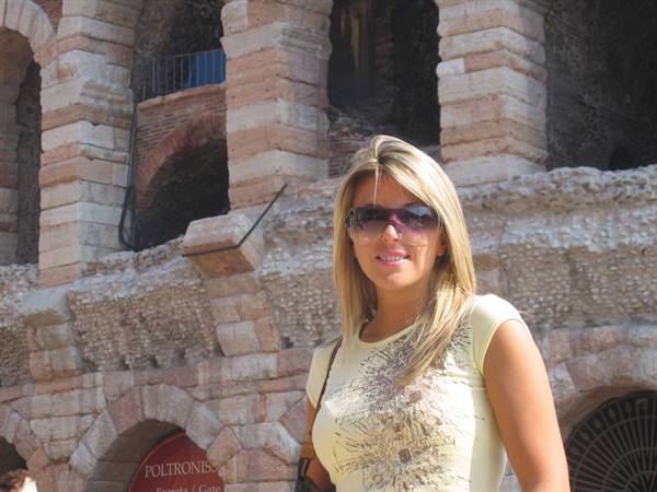 Blonde woman wearing sunglasses in front of Verona's brick Roman amphitheater