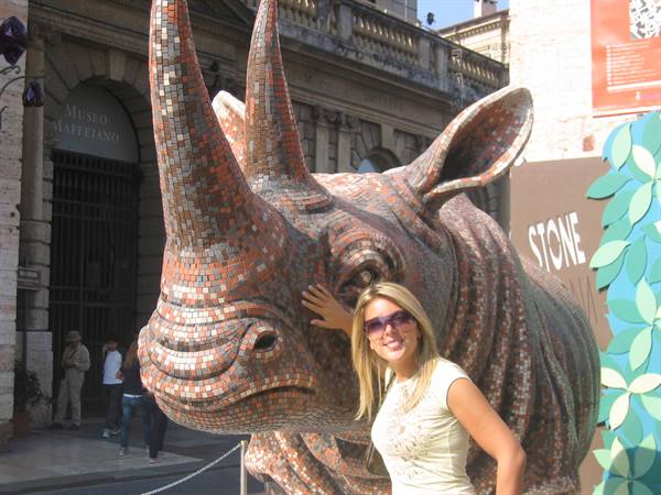 Woman touching a mosaic rhino sculpture outside the Maffeiano Museum in Verona