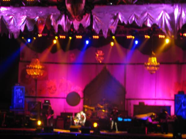 Stage lit with purple lights and golden chandeliers, musicians performing concert