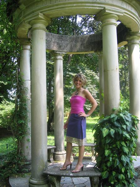 Woman in pink top posing among circular temple columns in a park