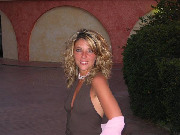 Smiling blonde woman in brown top in front of arched wall