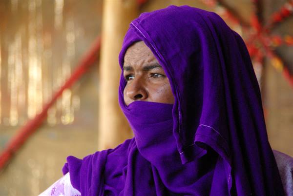 Tuareg woman in purple veil inside a tent, warm light