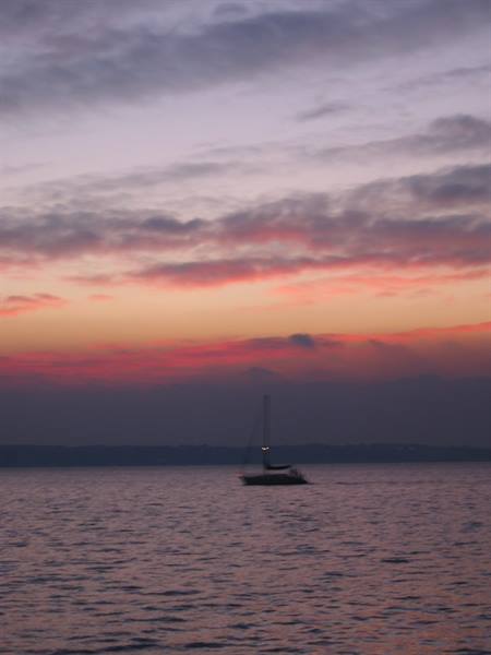 Sailboat silhouetted on calm sea at dusk