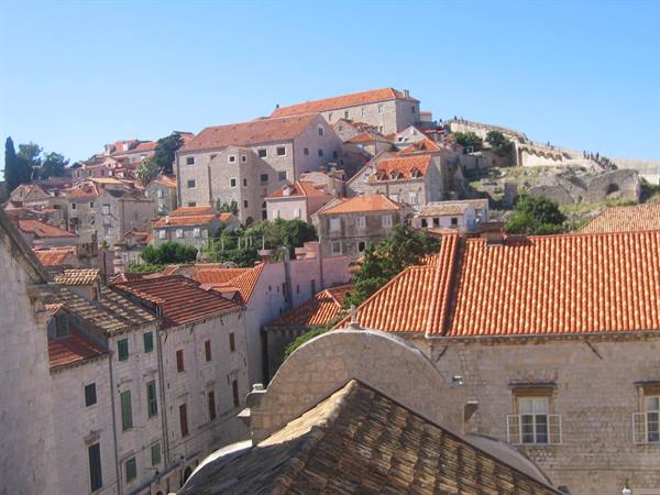 Red rooftops of Dubrovnik old town, pale stone houses under blue sky