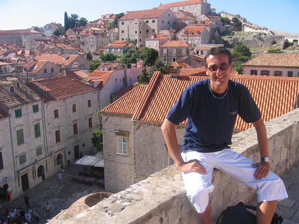 Smiling tourist on Dubrovnik rooftops, stone houses and red tiles