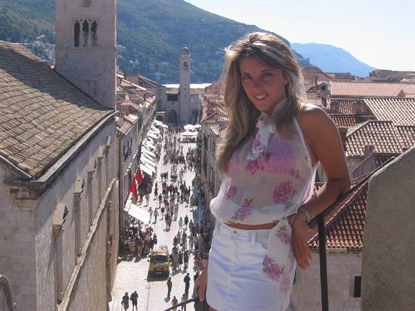 Smiling tourist on Dubrovnik walls, crowded Stradun street below