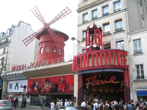 The Moulin Rouge in Paris, tourists at the entrance beneath the red windmill