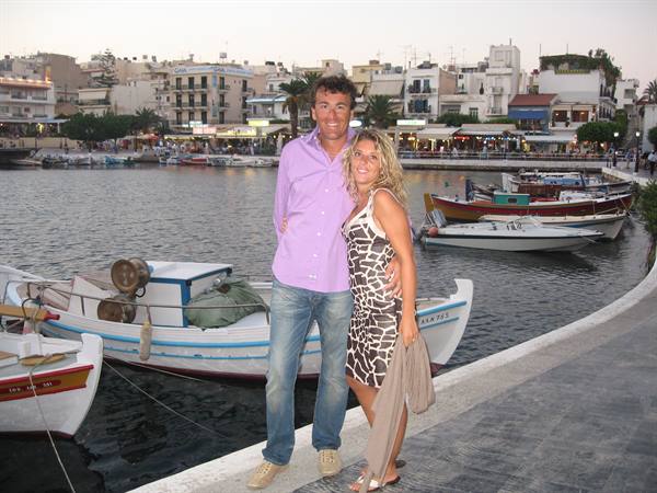 Couple on the quay of Agios Nikolaos harbor, fishing boats and evening lights