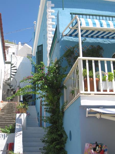 White spiral staircase beside bright blue house with flowering bougainvillea