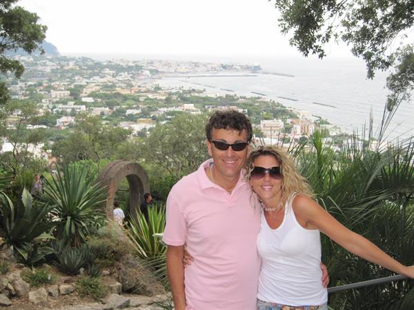 Smiling couple among agaves, Ischia bay and harbor behind them