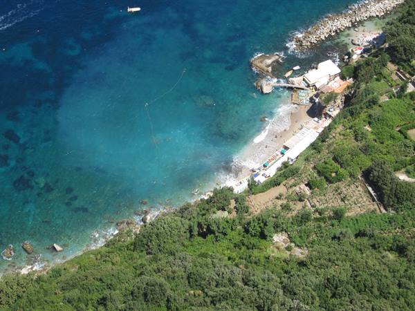 Sandy beach with bathing facilities amid green vegetation and turquoise sea