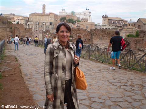 Smiling woman in plaid coat walks the ancient stone path of the Roman Forum