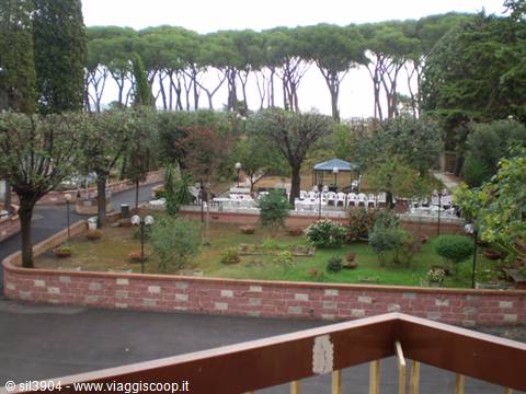 Garden with maritime pines, gazebos and white chairs seen from a terrace