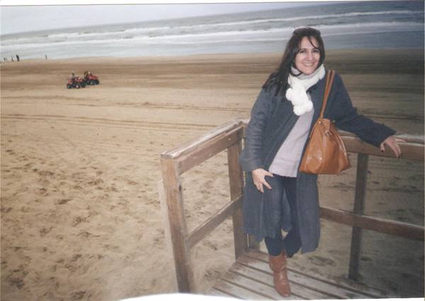Woman with brown bag and white scarf on wooden boardwalk by the beach