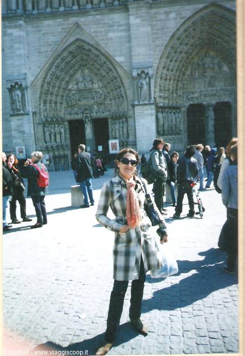 Smiling tourist in plaid coat in front of Notre-Dame portals, Paris