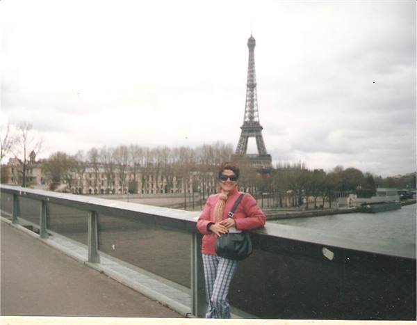 Woman with bag leaning on a bridge railing over the Seine, Eiffel Tower behind