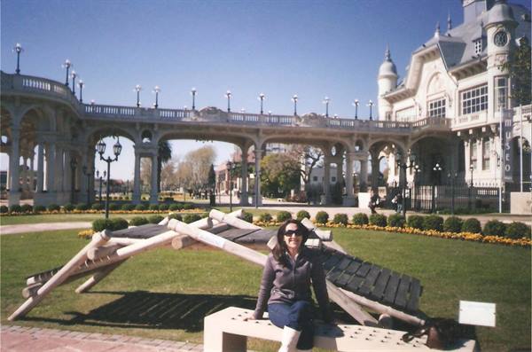 Woman sitting on bench in front of the Tigre Art Museum, white arched building