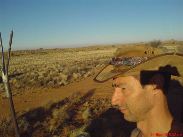 Man in leather hat gazing at sandy scrubland under bright sun