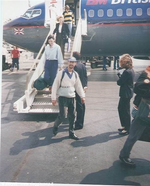Passengers disembark from a British Midland plane via mobile stairs, sunlit tarmac