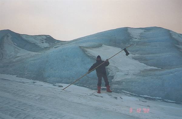 Glacier hike: person with long pole among blue crevasses and snow