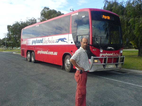 Man standing in front of a red Greyhound Australia coach bound for Perth