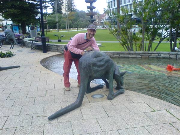 Tourist posing beside a bronze kangaroo sculpture in Perth