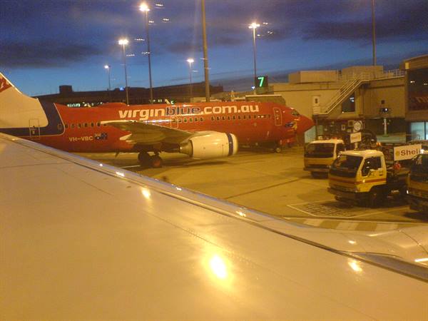 Red Virgin Blue jets at night gate, Shell trucks and lit wing