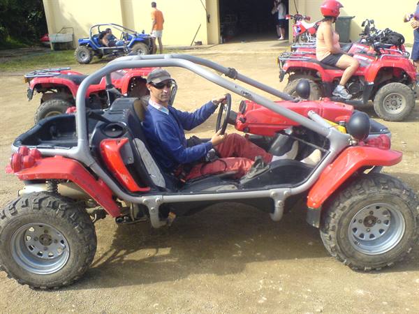 Man in red helmet driving a red dune buggy on dirt ground
