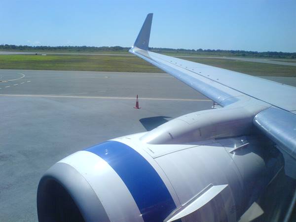 Aircraft wing and blue engine taxiing on the tarmac