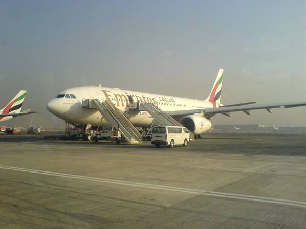 Emirates plane with boarding stairs and white van on the airport apron
