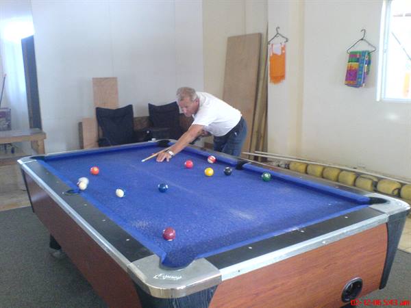 Man in white shirt playing pool on blue felt table