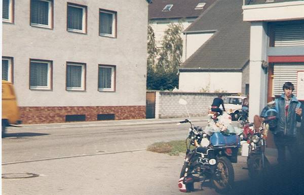 Boy in blue jacket beside loaded motorcycles on a neighborhood street